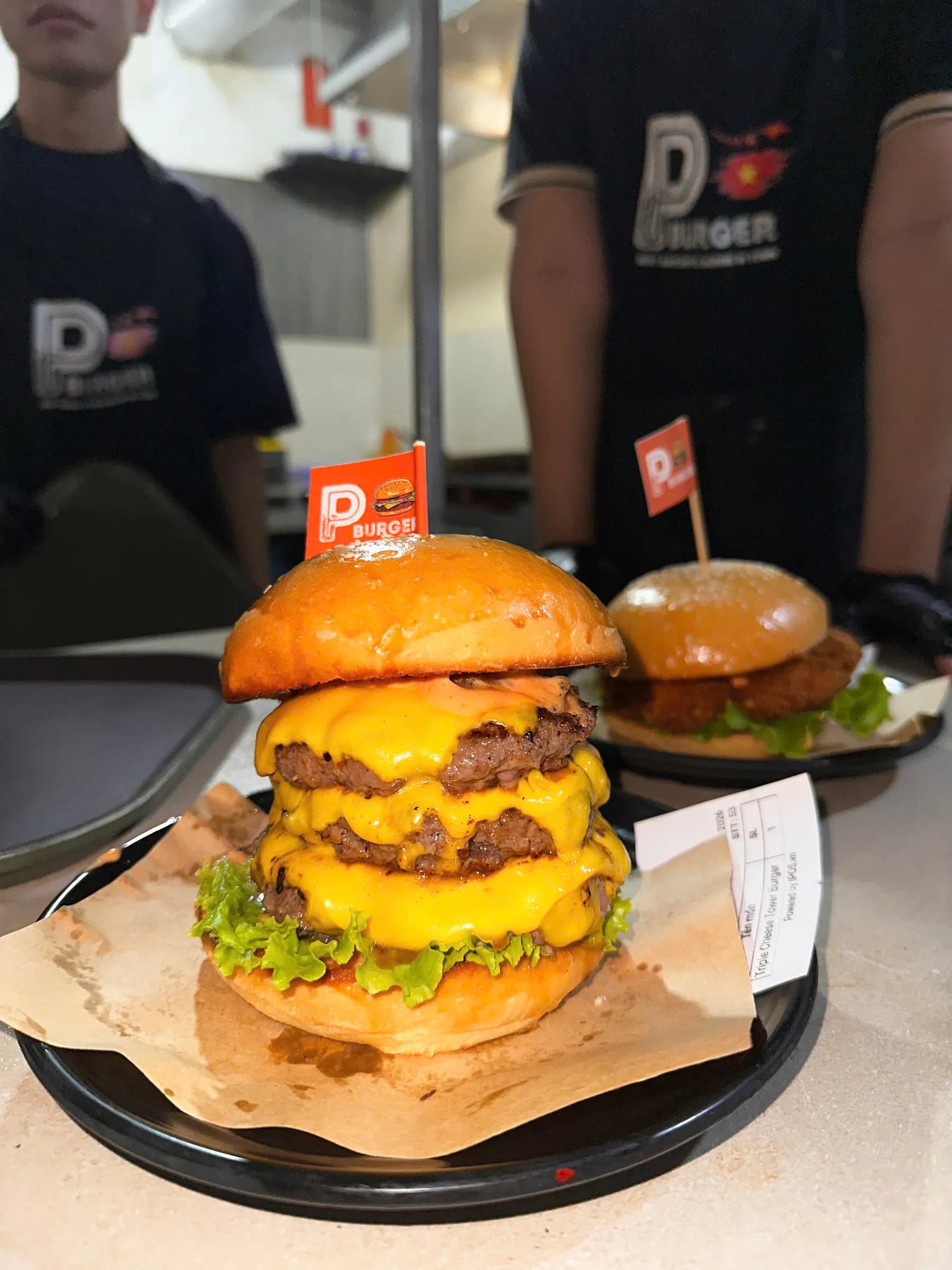 The P Burger crew holding a Triple Cheese Tower Burger